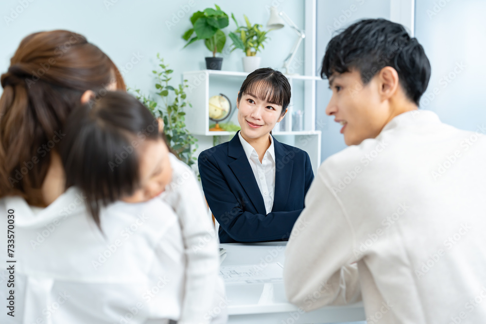 住宅の模型を見て話す親子と営業をする女性 住宅の模型を見て話す親子と営業をする女性