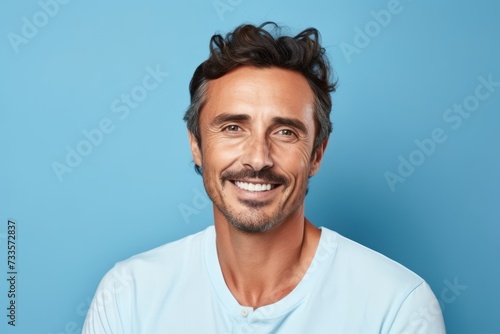 Portrait of handsome man smiling and looking at camera against blue background
