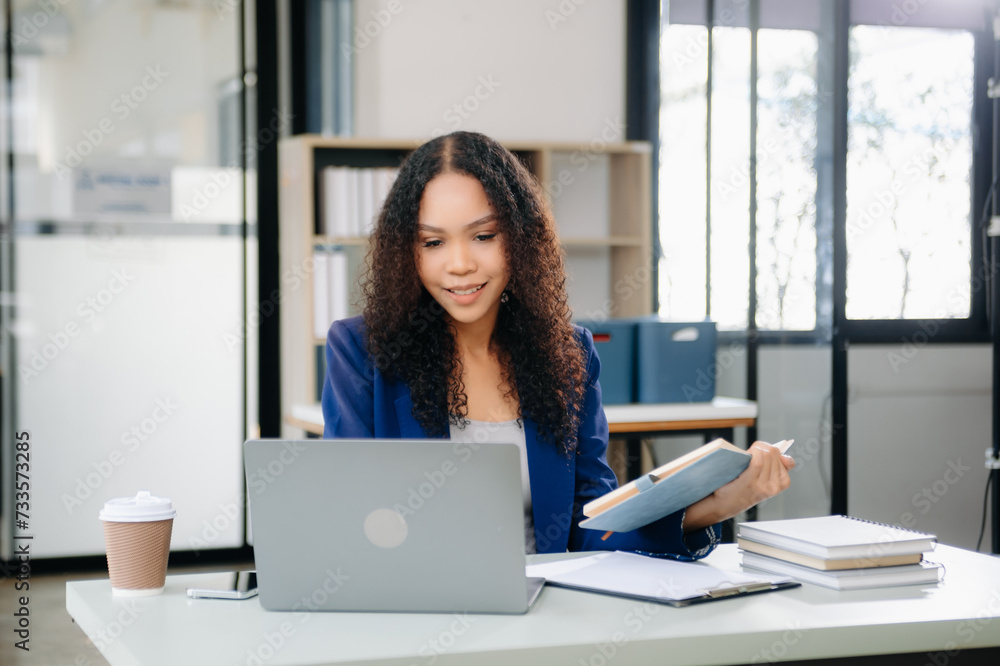Confident business expert attractive smiling young woman typing laptop and holding digital tablet on desk Confident business expert attractive smiling young woman typing laptop and holding digital tablet on desk
