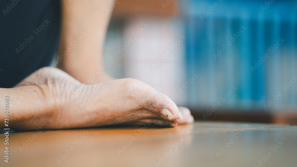 The bare feet of an old man sitting on a wooden table show wrinkled skin. The bare feet of an old man sitting on a wooden table show wrinkled skin.