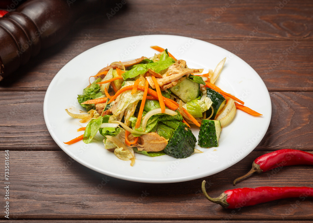 Salad of chicken, lettuce, carrots and cucumbers. On a wooden background. Salad of chicken, lettuce, carrots and cucumbers. On a wooden background.