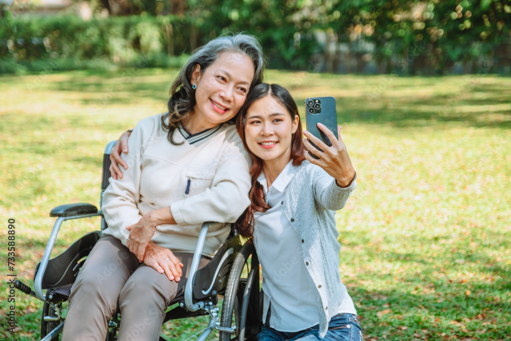 Obraz premium Asian grandmother in wheelchair with daughter is enjoying at the park in the morning