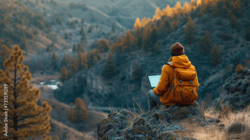 Outdoor Mobile Office in the Mountains: A person sitting with a laptop on a remote mountain overlook, blending work with the love for the outdoors and adventure.