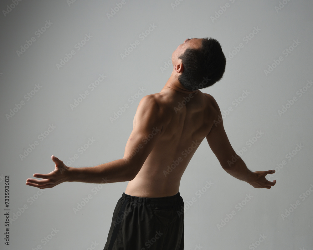 Close up portrait of fit asian male model, shirtless with muscles. gestural ti chi inspired posing with arms reaching out. Isolated on a white studio background with moody silhouette. Close up portrait of fit asian male model, shirtless with muscles. gestural ti chi inspired posing with arms reaching out. Isolated on a white studio background with moody silhouette.