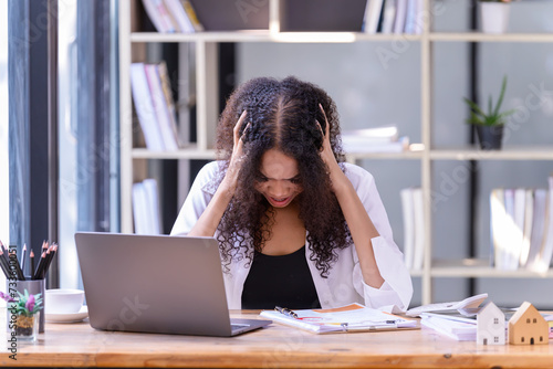 Businesswomen are stressed with work in front of a laptop and paper documents in the office.