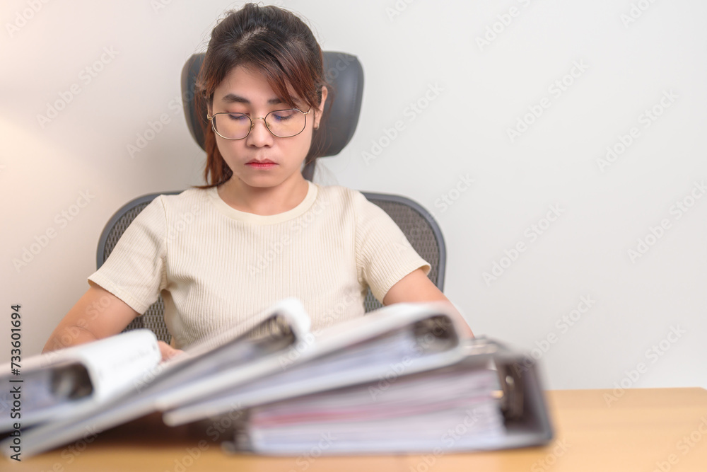 Asian woman having Tired and Stressed while working, female businesswoman having headache and Migraine at office, Exhausted woman with document folder stack at home late night. Overworked and Overtime Asian woman having Tired and Stressed while working, female businesswoman having headache and Migraine at office, Exhausted woman with document folder stack at home late night. Overworked and Overtime