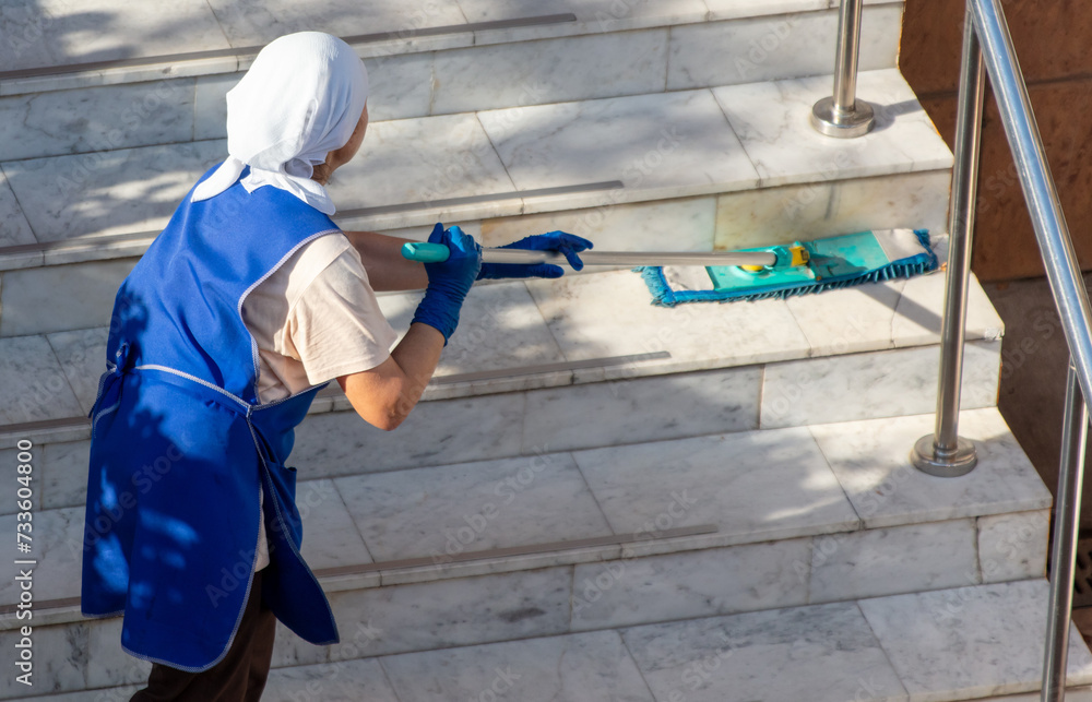 A woman washes the floor on the stairs in a building