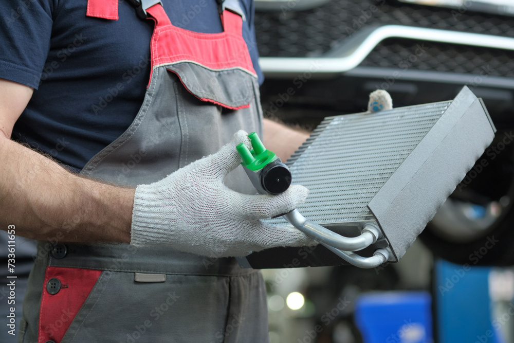 Major repairs of the car. Radiator replacement. An auto mechanic performs quality control of a new radiator before installation. Major repairs of the car. Radiator replacement. An auto mechanic performs quality control of a new radiator before installation.