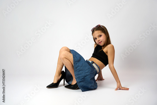 Portrait of a cute girl wearing high heels shoes and denim skirt with summer top.