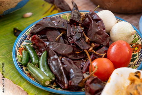 Chile jalapeño, chile guajillo, jitomates y cebollas juntos en un plato photo