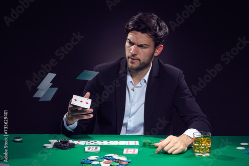 Addiction Concepts. Angry Depressed Handsome Caucasian Brunet Pocker Player At Pocker Table With Chips and Cards Drinking Alcohol And Throwing Cards Away.