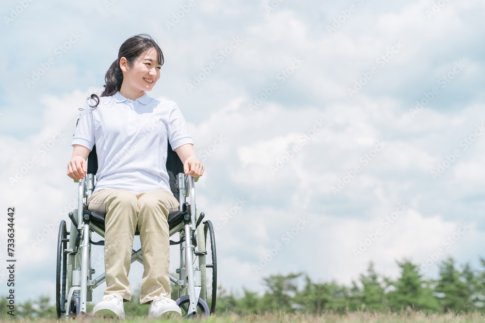 車椅子に座る笑顔の日本人女性（青空）
