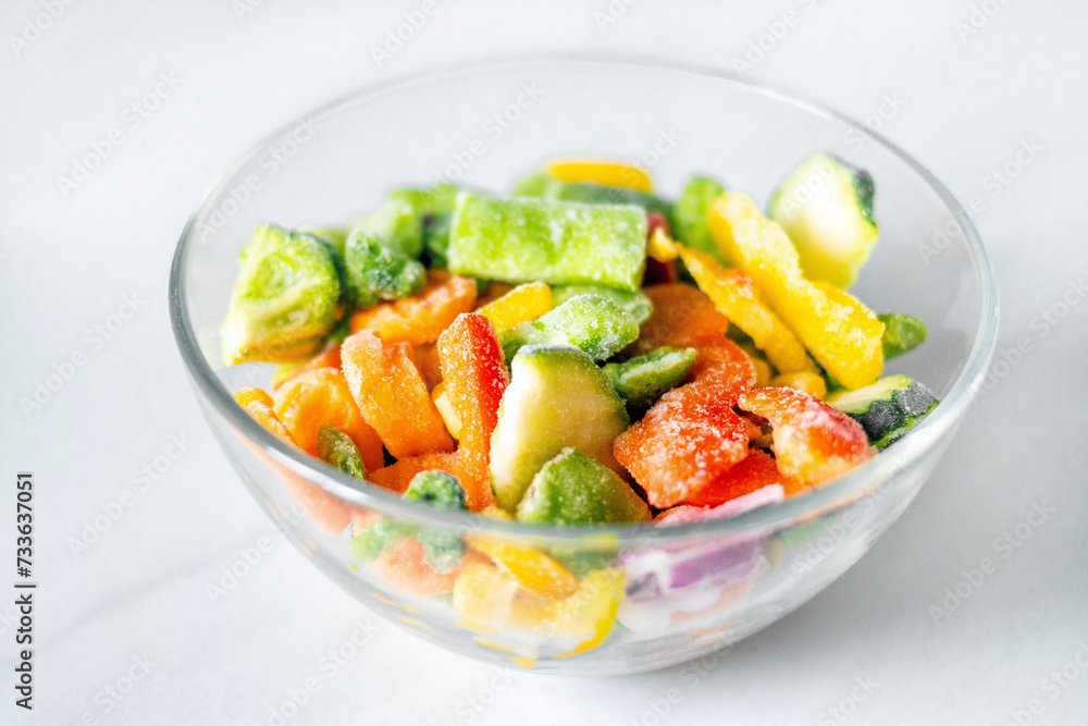 Frozen vegetables in a glass plate on a white background. The concept of healthy eating