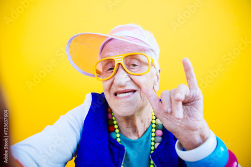 Funny grandmother portraits. 80s style outfit. trapstar taking a selfie on colored backgrounds. Concept about seniority and old people photo