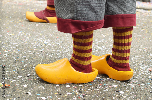 Carnival street parade in Germany. Witch legs in orange wooden shoes and striped socks.
