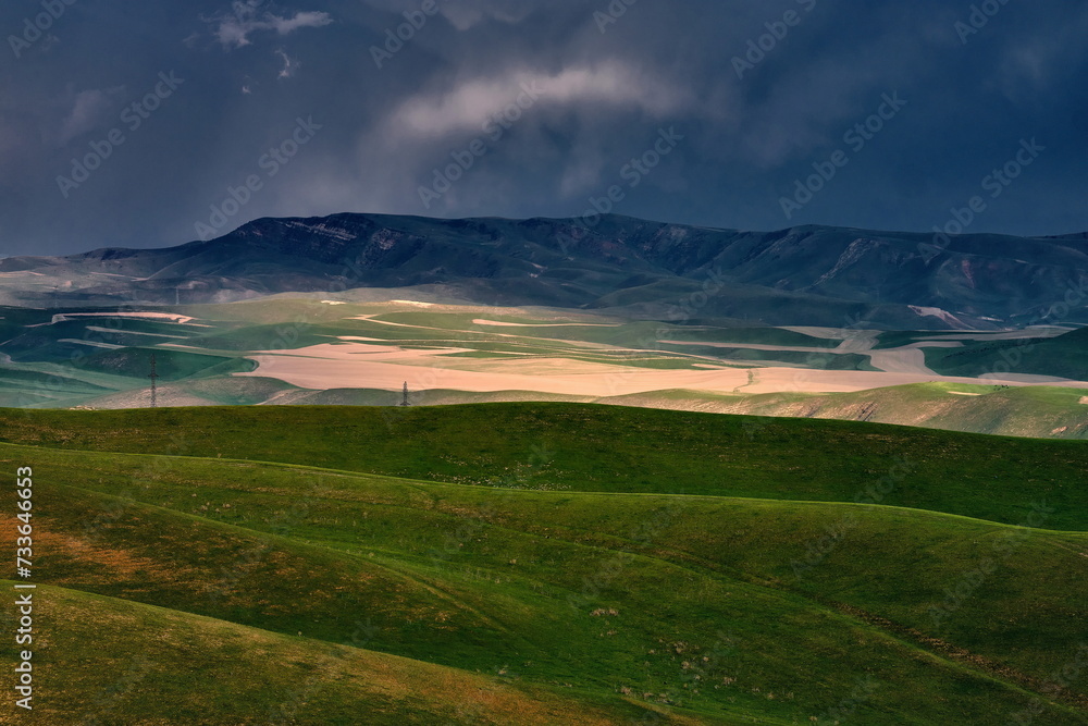An epic landscape of spring hills against an approaching storm.