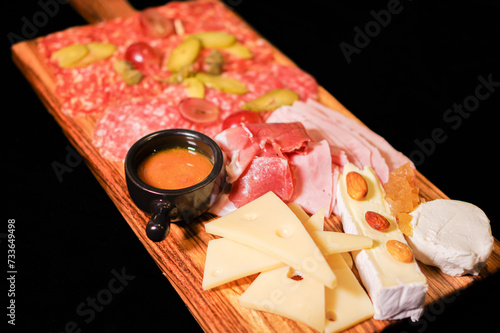 charcuterie meat and cheese tray with cold cut, pickled cucumber, olive and nuts antipasto board isolated with black background