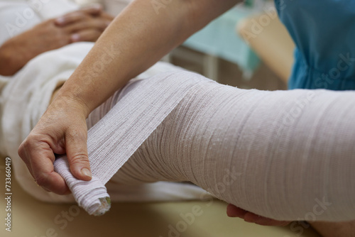 doctor bandages patient's leg in emergency room, leg injury