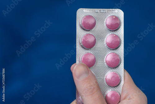 Blister z różowymi tabletkami trzymany w dłoni izolowany
