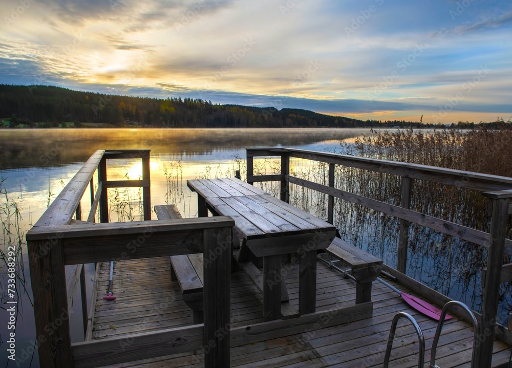 wooden dock with a table at the edge of a lake at dusk in beautiful Sweden landscape