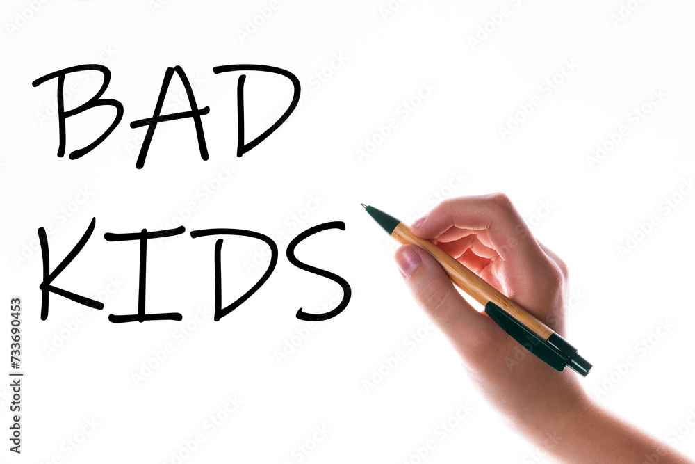 Children hand with pen write on an blue white background. Writing hand. Word Bad kids