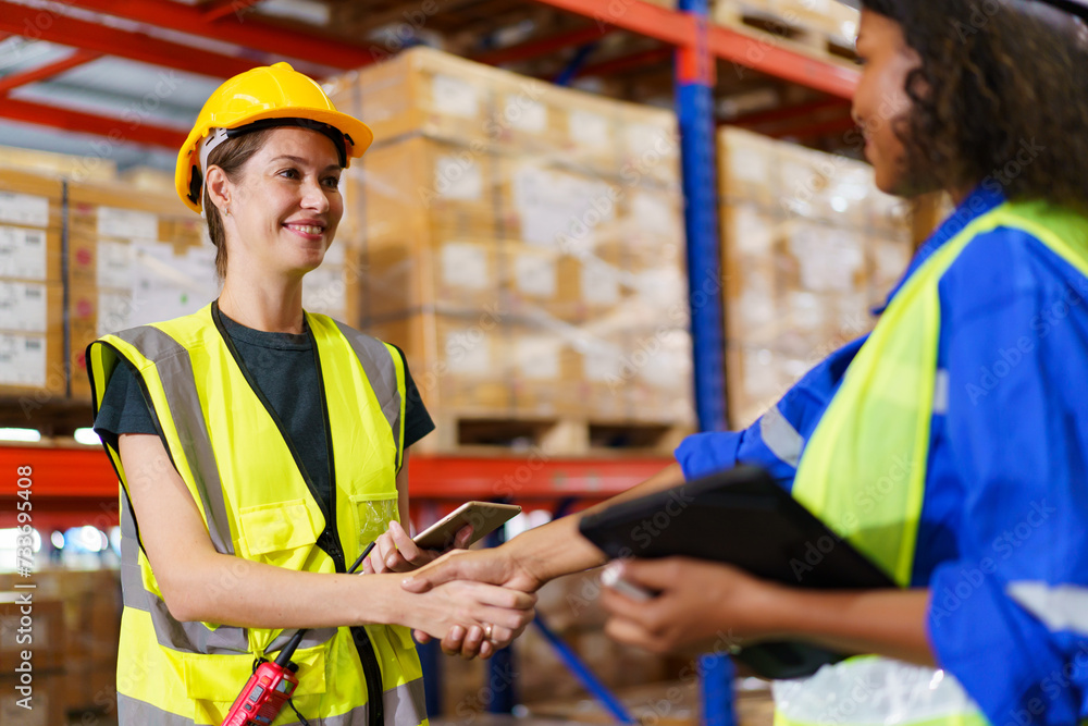 female warehouse officer making a handshake with her team staff in warehouse. female warehouse officer making a handshake with her team staff in warehouse.