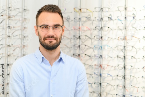 Healthcare, Eyesight And Vision Concept. Happy man choosing glasses at optics store, selective focus © Serhii