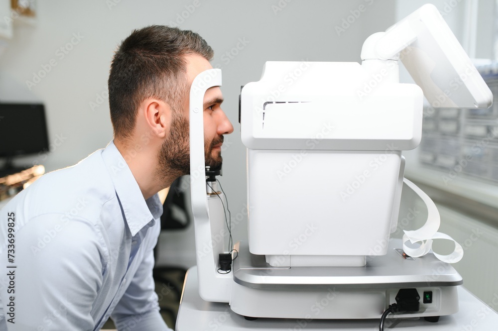 Handsome young man is checking the eye vision in modern ophthalmology clinic. Patient in ophthalmology clinic Handsome young man is checking the eye vision in modern ophthalmology clinic. Patient in ophthalmology clinic