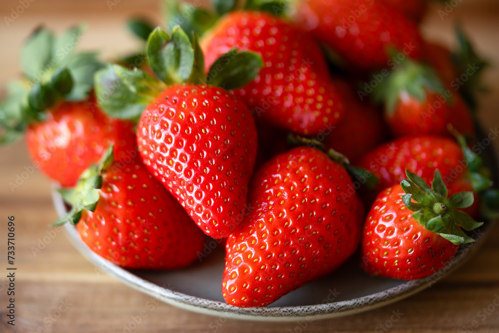 Strawberries in a plate on a wooden table. Strawberries background. Top view. Macro photography. Healthy food Strawberries in a plate on a wooden table. Strawberries background. Top view. Macro photography. Healthy food