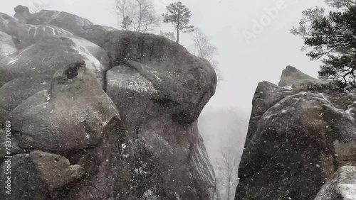Dovbush rocks in winter in Bubnyshche, Carpathians, Ukraine, Europe. Huge stone giants rise above the forest, with a unique illusion of a bear's head on them, which appeared during a storm photo