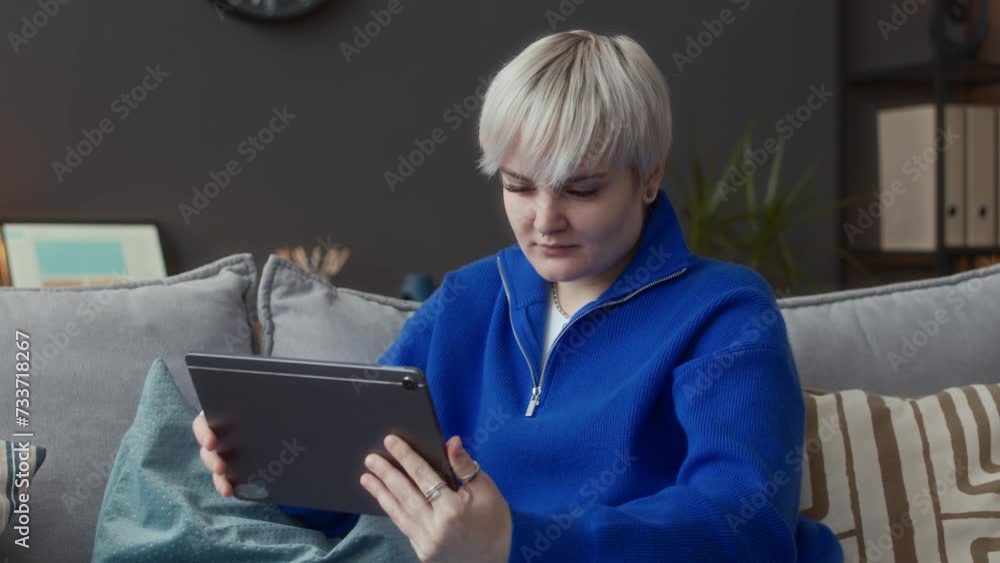 Waist up of young Caucasian woman looking at herself in digital tablet front camera while preparing for online video conversation from home Waist up of young Caucasian woman looking at herself in digital tablet front camera while preparing for online video conversation from home