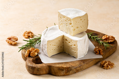 Caciotta, creamy, soft italian cheese. A beginner cheese on a wooden board, with walnuts and rosemary.
