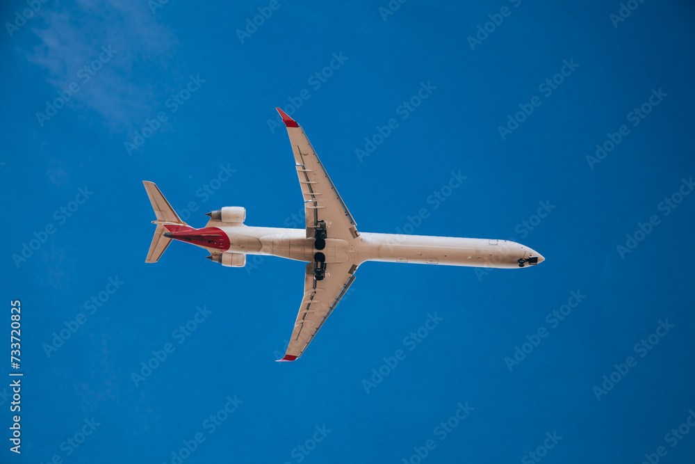 Fototapeta premium Passenger plane in flight. Bottom view of a red passenger plane flying above the clouds.