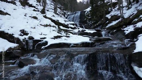 View of a waterfall during winter. Cold and frost in the forest. Winter adventure and hiking. Kozice Waterfall near Fojnica in Bosnia and Herzegovina. photo