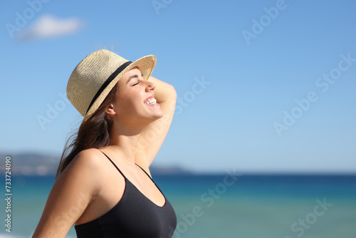 Happy woman with hat breathing on the beach