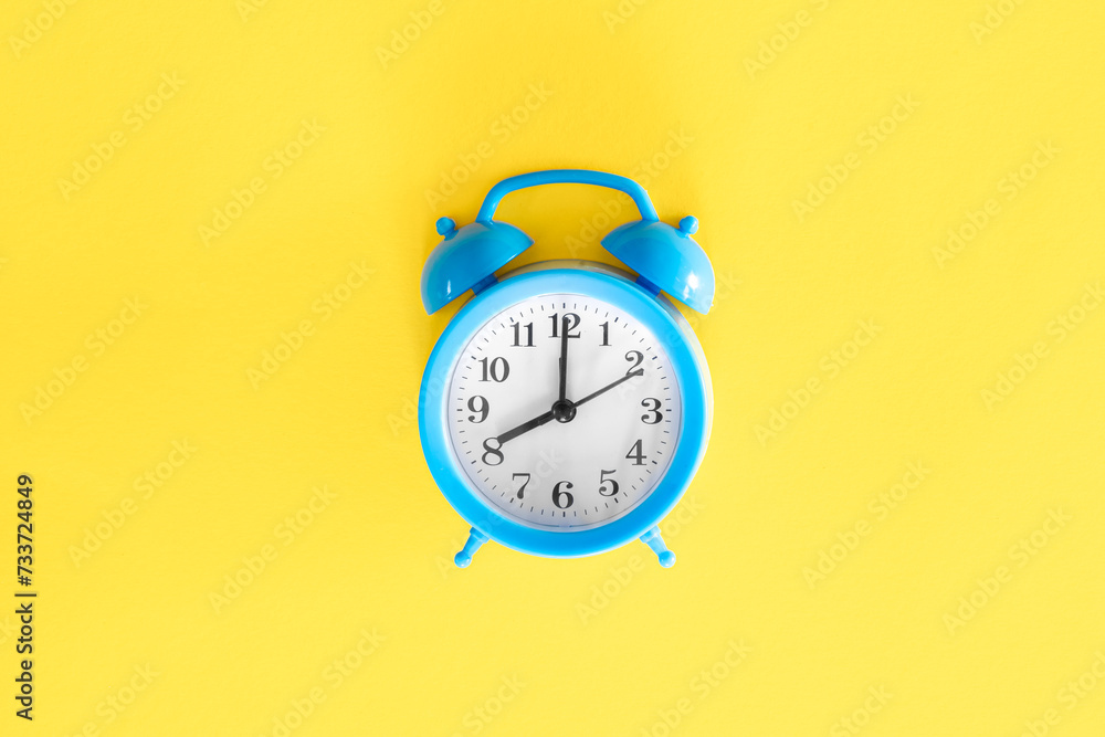 Blue alarm clock on a yellow background, top view. Blue alarm clock on a yellow background, top view.