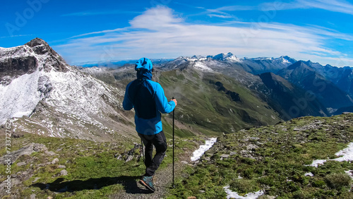 Hiker man with scenic view of majestic mountain peaks of High Tauern seen from Feldseekopf, Carinthia Salzburg, Austria. Idyllic hiking trail in Goldberg group in wild remote Austrian Alps. Wanderlust photo