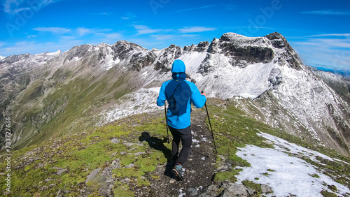 Hiker man with scenic view of majestic mountain peaks of High Tauern seen from Feldseekopf, Carinthia Salzburg, Austria. Idyllic hiking trail in Goldberg group in wild remote Austrian Alps. Wanderlust