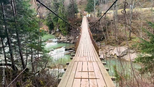 Suspension bridge in the Carpathians, Ukraine over the Prut River, in the village of Mykulychyn, Tatariv, leads to the trail to Mount Khomyak, Synyak in Gorgany, as well as to the Guk Waterfall photo