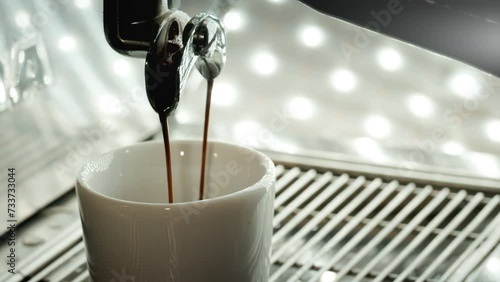 Espresso pouring to cup from coffee maker machine. photo