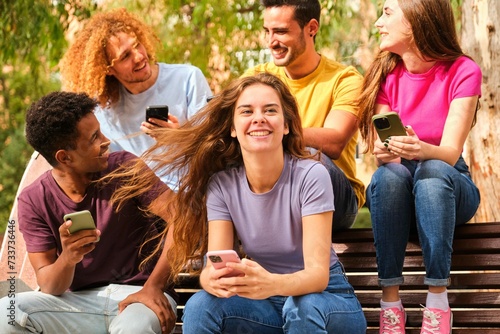 Group teenagers holding mobile phones watching video, communication online, chatting at street.