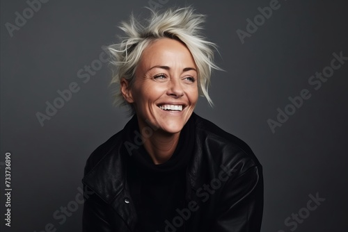 Portrait of a smiling senior woman in black leather jacket, studio shot