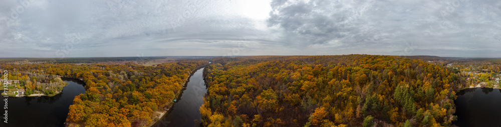 Autumn aerial wide panorama of river valley and colorful golden forest. Autumnal vibrant trees in rural riverside in Ukraine