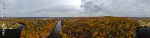 Autumn aerial wide panorama of river valley and colorful golden forest. Autumnal vibrant trees in rural riverside in Ukraine