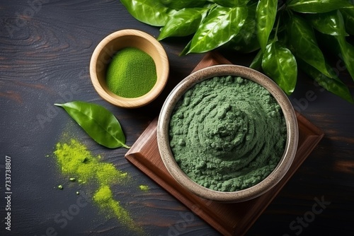Green spirulina tablets in a bowl and powder in the background photo