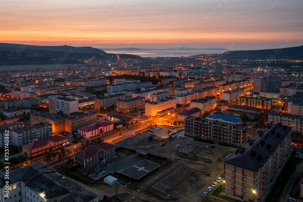 Morning aerial photograph of the city. Top view of the streets and buildings. Dawn. Empty streets and yards. In the distance the sea and hills. City of Magadan, Magadan region, Far East of Russia.