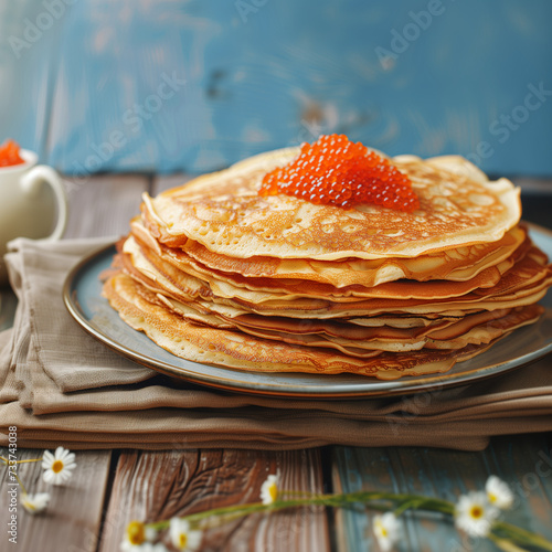 stack of traditional thin pancakes on a plate with red caviar on wooden table