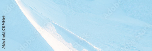 Snow texture. Wind sculpted patterns on snow surface. Wind in the tundra and in the mountains on the surface of the snow sculpts patterns and ridges (sastrugi). Arctic, Polar region. Winter background photo