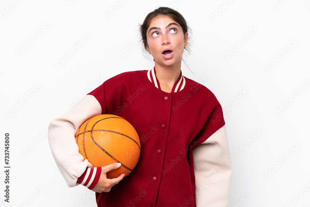 Young basketball player woman isolated on white background looking up and with surprised expression