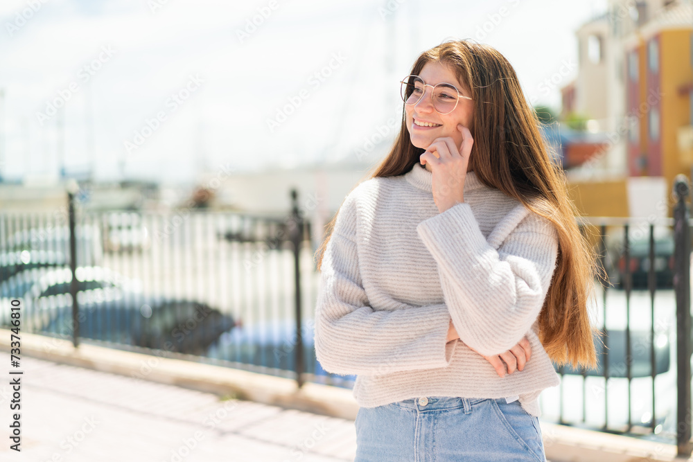 Young pretty caucasian woman with glasses at outdoors looking to the side